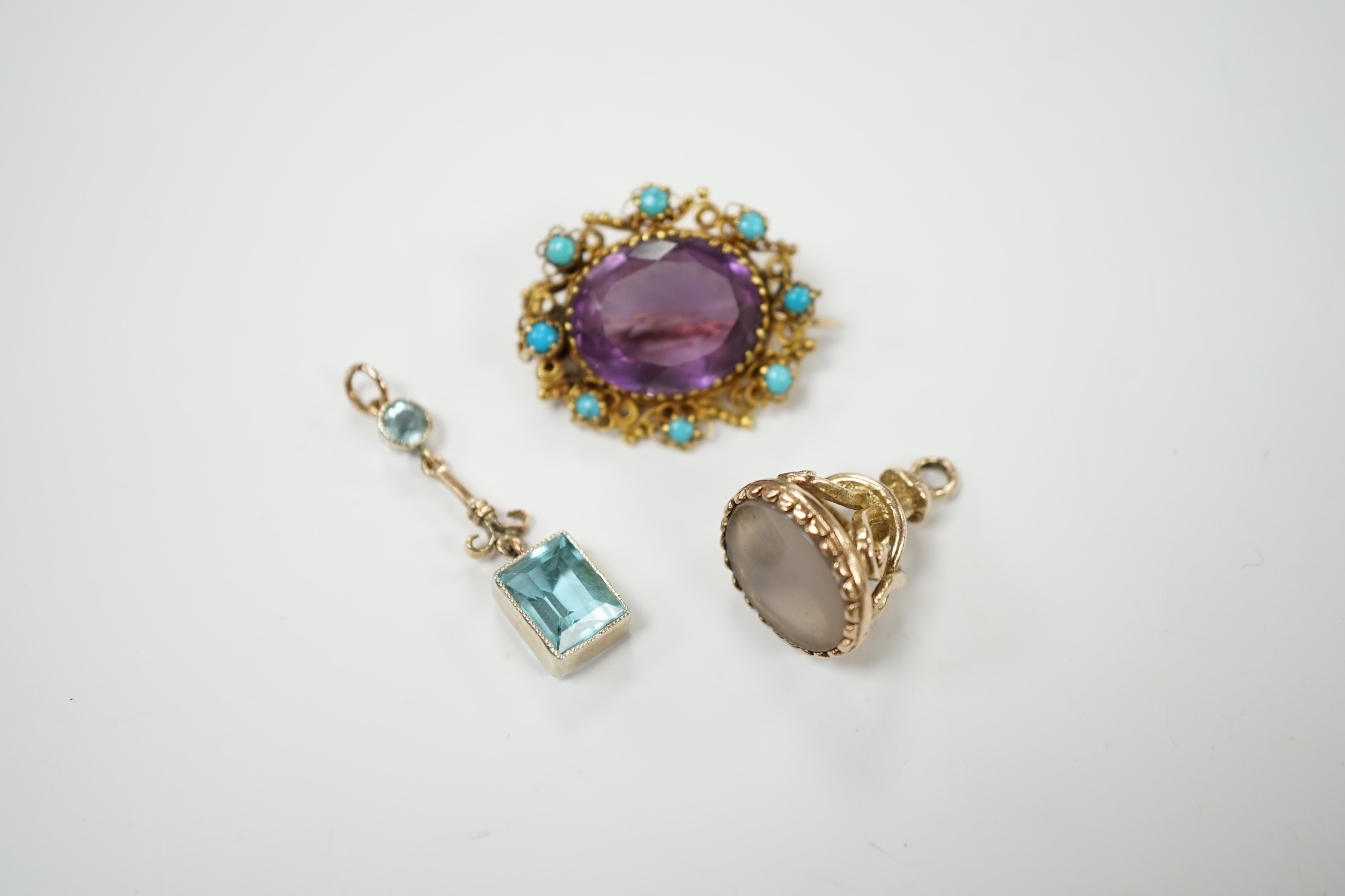 An early 20th century yellow metal, amethyst and turquoise set brooch, 25mm, a 9ct gold and white chalcedony set fob and a yellow metal and gem set drop pendant. Condition - poor to fair